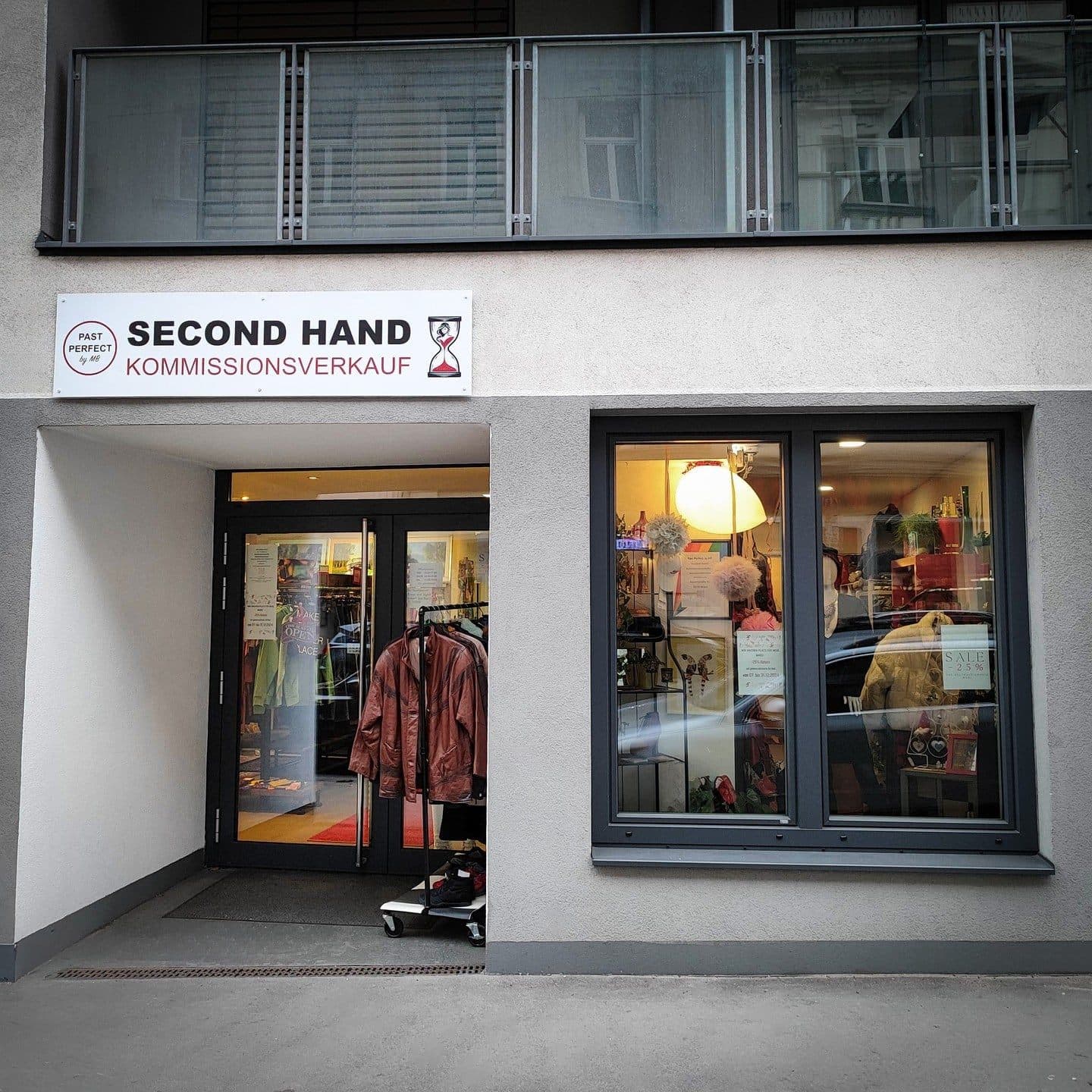 Geschäftsschild mit Schriftzug Past Perfect Second Hand Kommissionsverkauf über dem Ladeneingang.