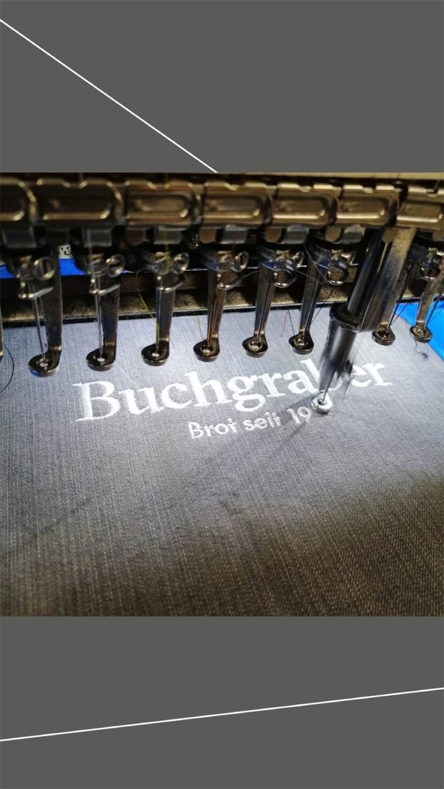 Nahaufnahme einer Stickmaschine beim Besticken eines Textils mit Firmen-Schriftzug.