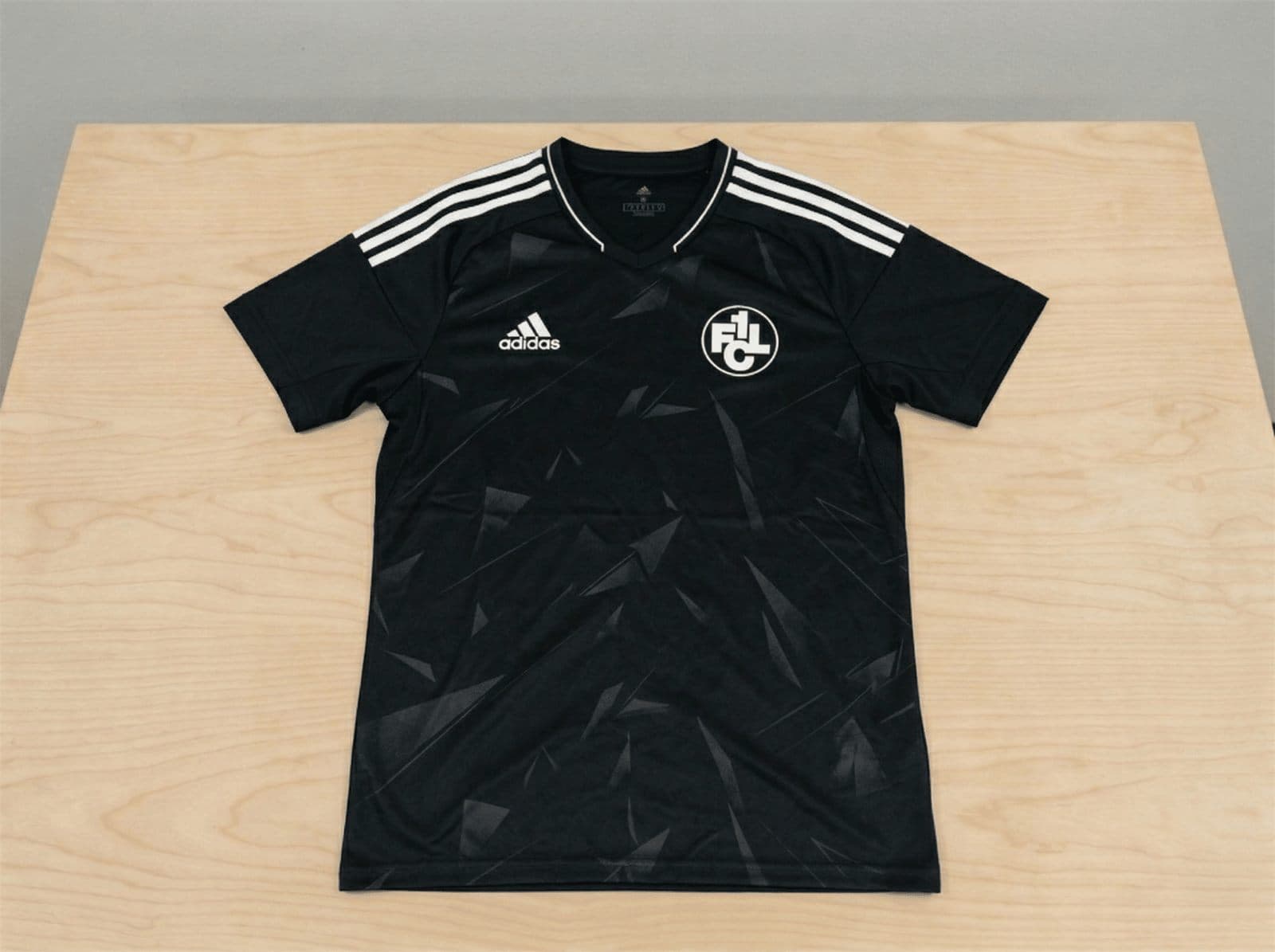 Schwarzes Adidas-Fußballtrikot mit FCL-Vereinslogo und weißen Streifen auf den Ärmeln.